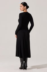 A woman is wearing a fitted, long-sleeve, ribbed black sweater paired with a matching ribbed black midi skirt. She is also wearing tall black leather boots with high heels. The outfit appears elegant and monochromatic.